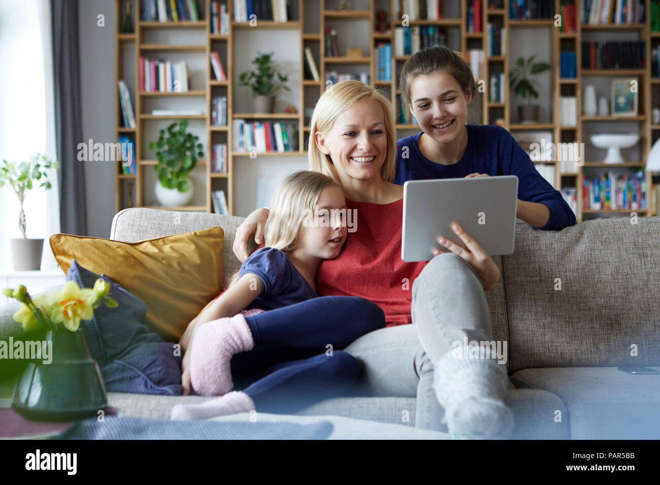 Madre e le sue figlie seduta sul lettino, divertirsi utilizzando notebook digitale Foto Stock