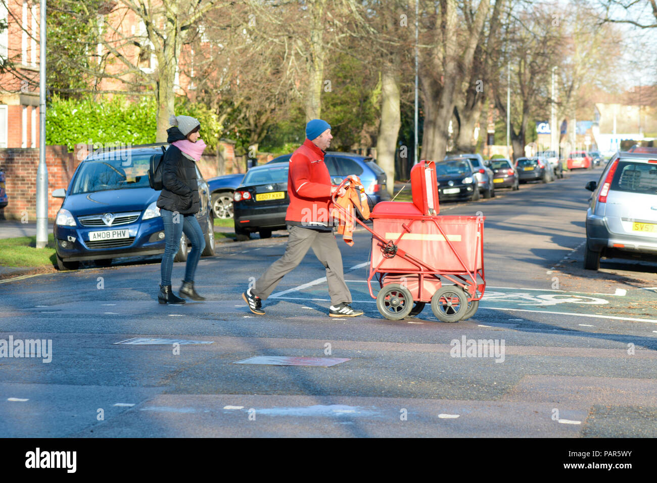 Royal Mail impiegato postale spingendo il carrello posta su strada in Bedford Bedfordshire Inghilterra Foto Stock