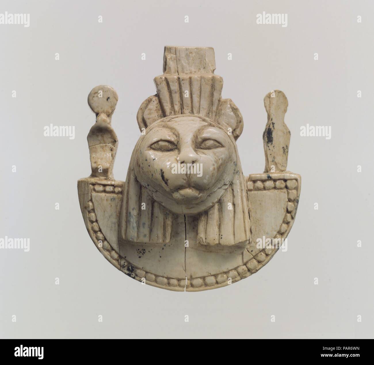 Openwork mobili placca con la testa di un felino. Cultura: Assiro l. Dimensioni: 2,09 x 1,89 x 0,94 in. (5,31 x 4,8 x 2,39 cm). Data: ca. 9th-8secolo A.C. Trovato in un ripostiglio a Fort Shalmaneser, un palazzo reale a Nimrud che è stata utilizzata per memorizzare il bottino e un tributo riscosso dagli Assiri mentre sulla campagna militare, questo pezzo raffigura la faccia frontale di un felino che indossa un bordato wesekh ampio collare affiancato da due rising sun-disc incoronato uraei (mitico, fire-sputare serpenti). Questa immagine è prelevata da arte egizia, dove la testa di un felino può rappresentare sia Bastet, la dea Foto Stock