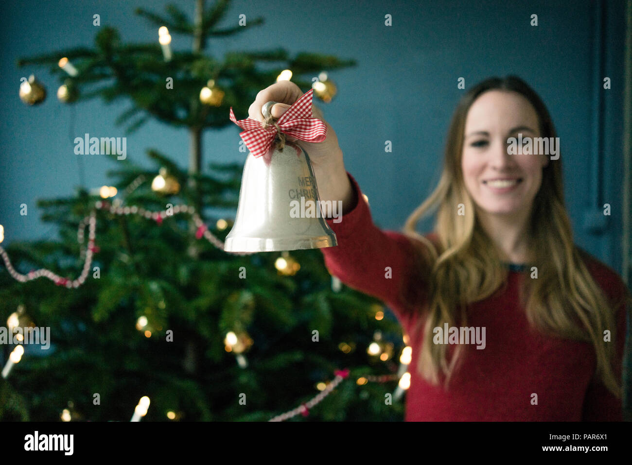 Donna sorridente che mostra argento campana di Natale Foto Stock