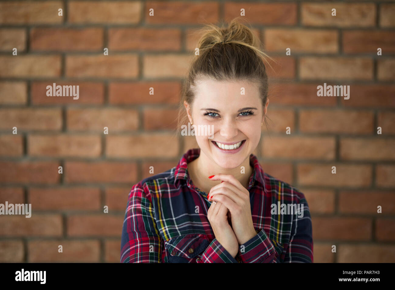 Ritratto di ridere giovane donna di fronte a un muro di mattoni Foto Stock