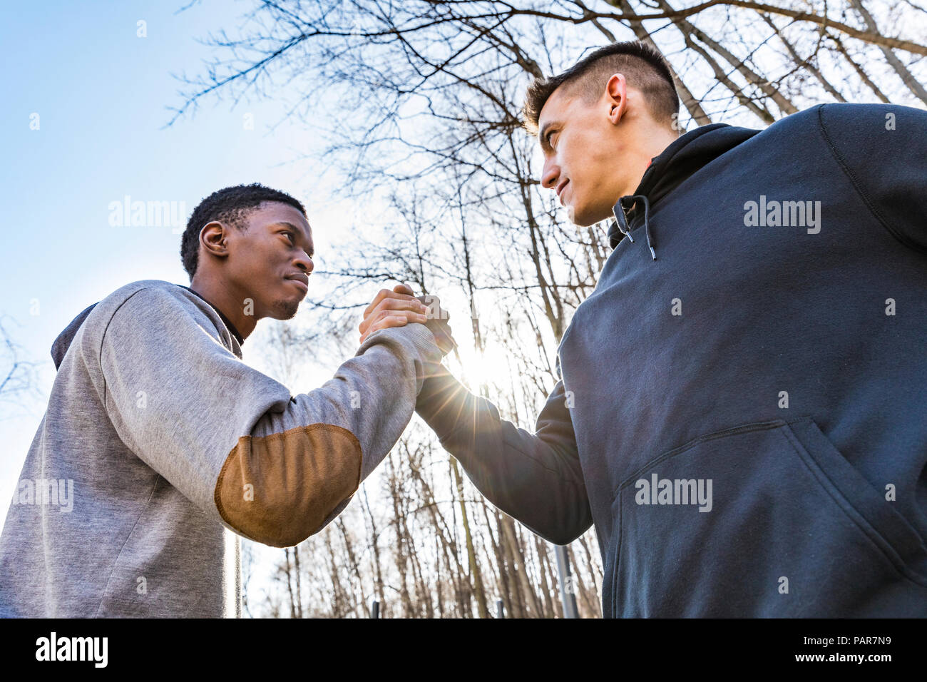 Due giovani sportivi uomini stringono le mani all'aperto Foto Stock