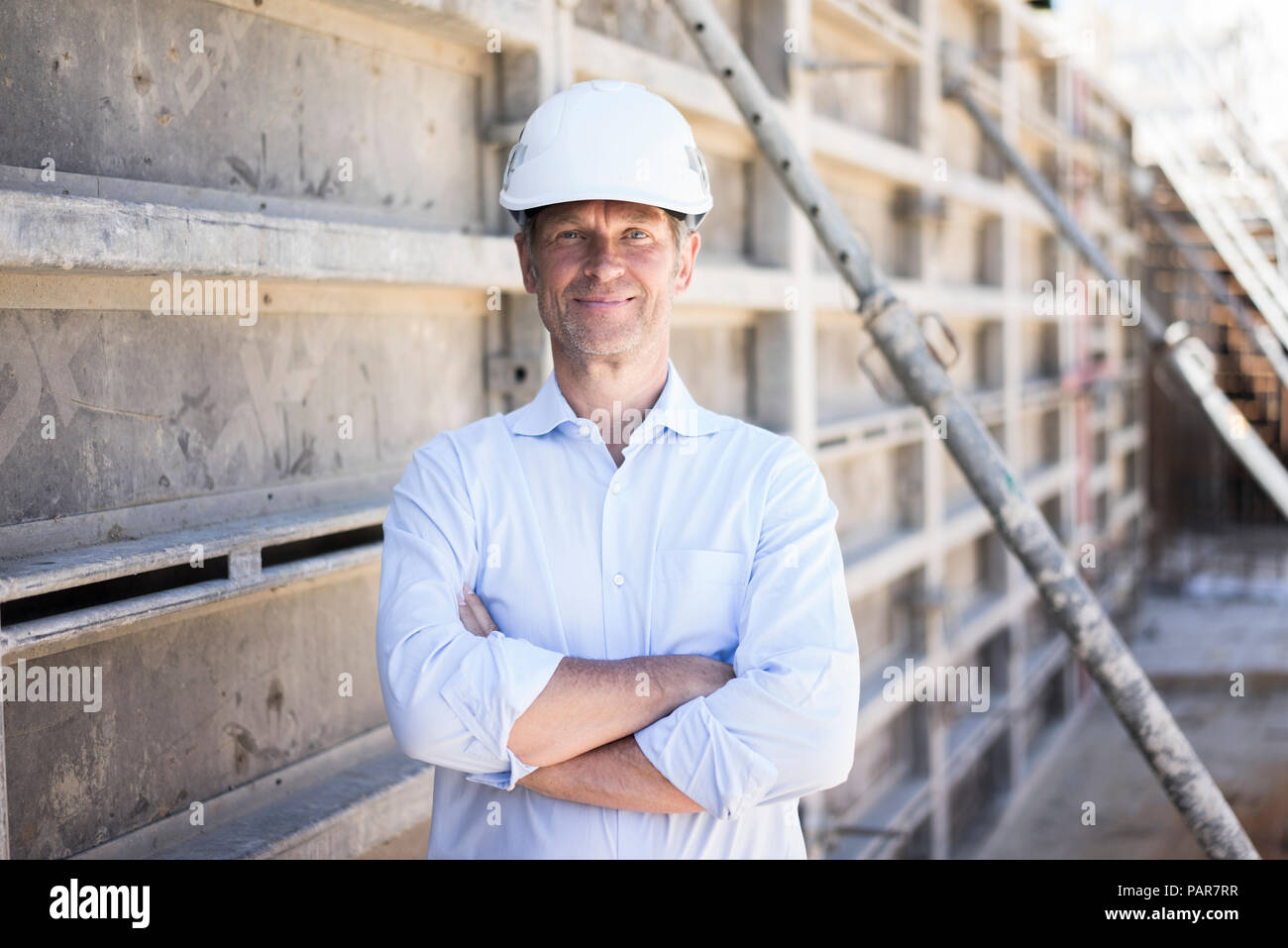 Ritratto di fiducioso uomo che indossa il casco sul sito in costruzione Foto Stock