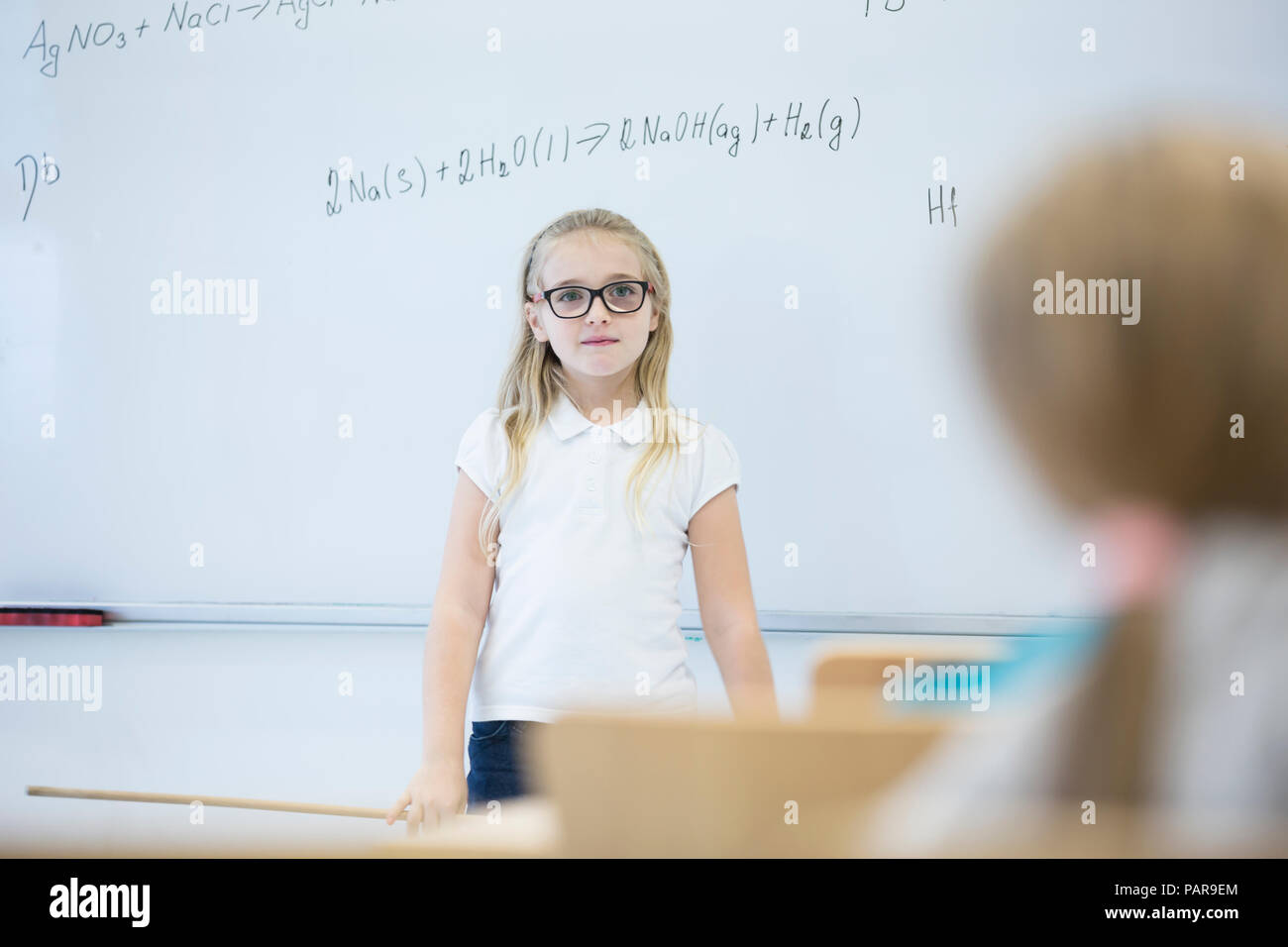 Schoolgirl in piedi alla lavagna con formula in classe Foto Stock
