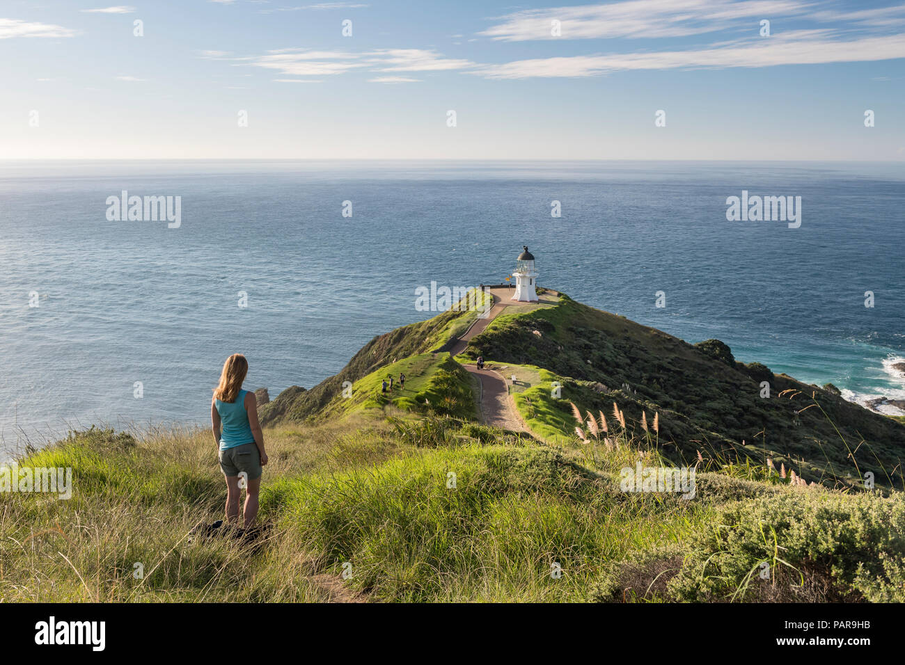 La donna sta di fronte al faro di Cape Reinga, Northland e North Island, Nuova Zelanda Foto Stock