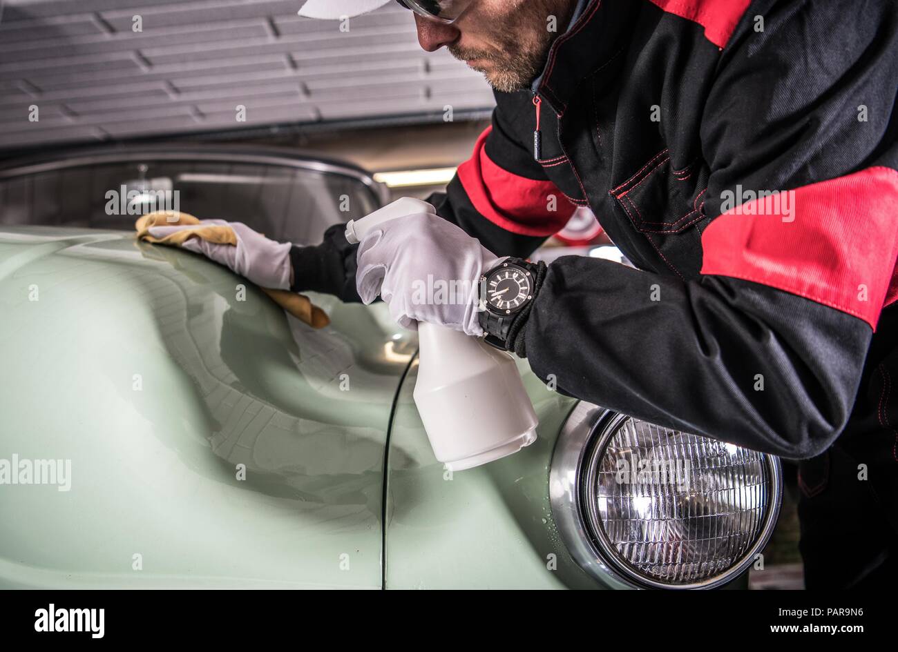 La pulizia degli uomini il suo corpo vettura usando detergente professionale nel liquido. Lavaggio del veicolo e illustrando il tema. Classic Car. Foto Stock