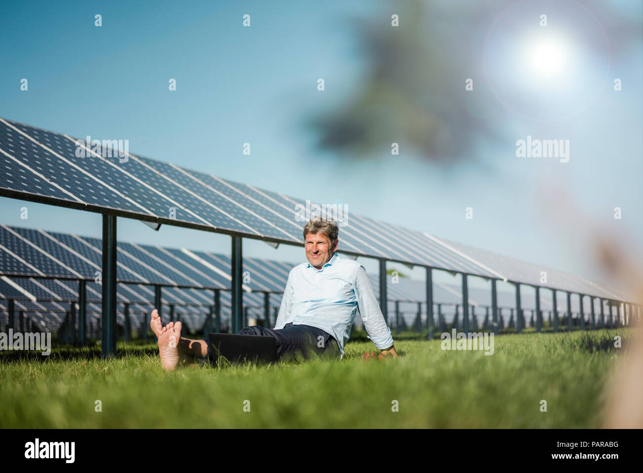 Coppia uomo seduto a piedi nudi sul prato, impianto solare Foto Stock