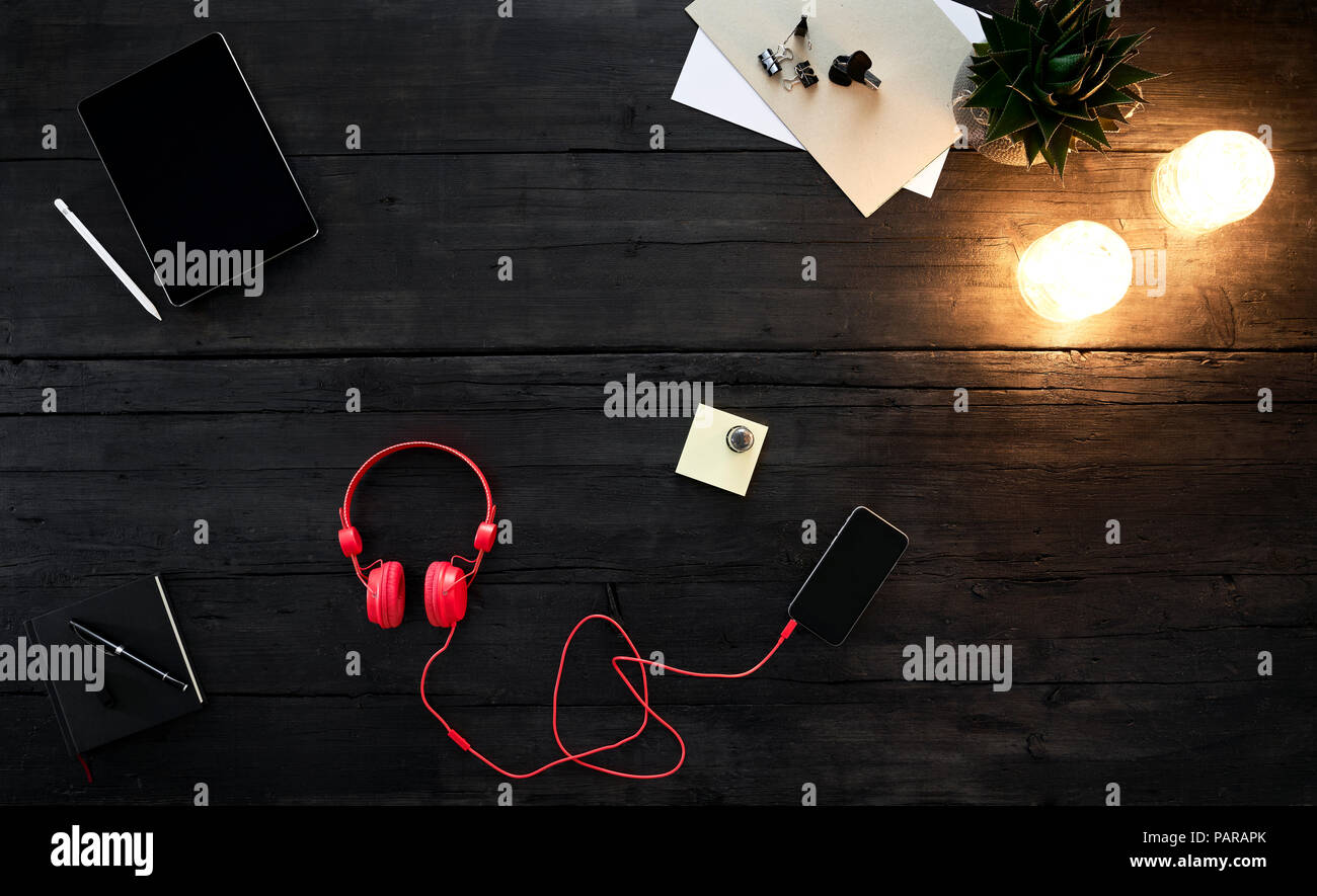 Red Headphones lo streaming di musica dallo smartphone, giacente sulla scrivania Foto Stock