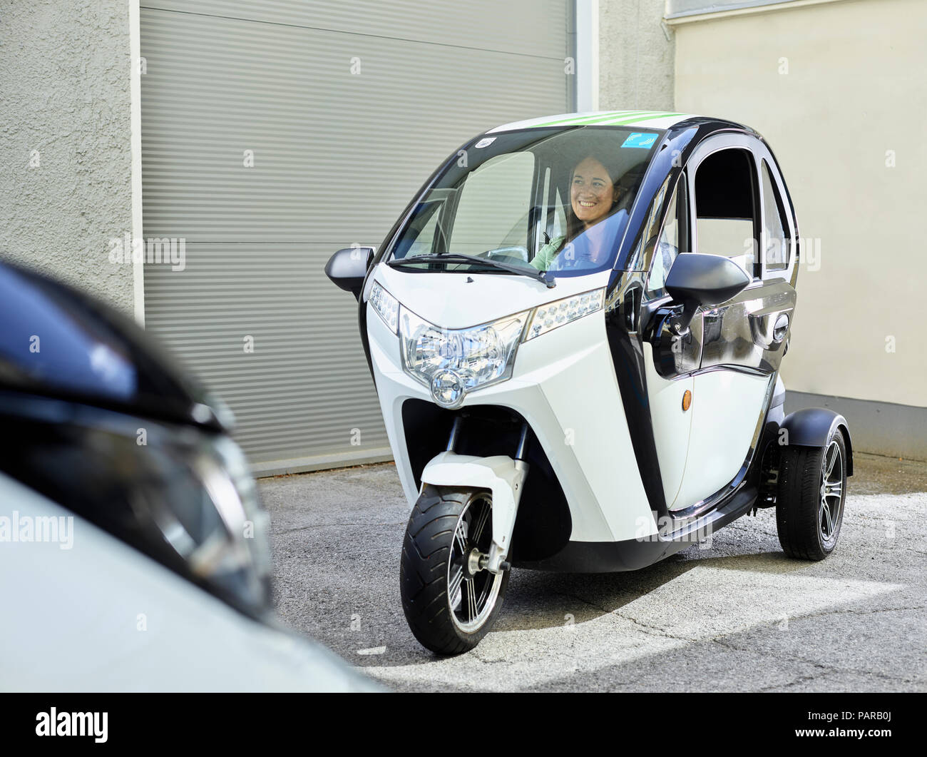 Donna sorridente seduto in bolla elettrico auto Foto Stock