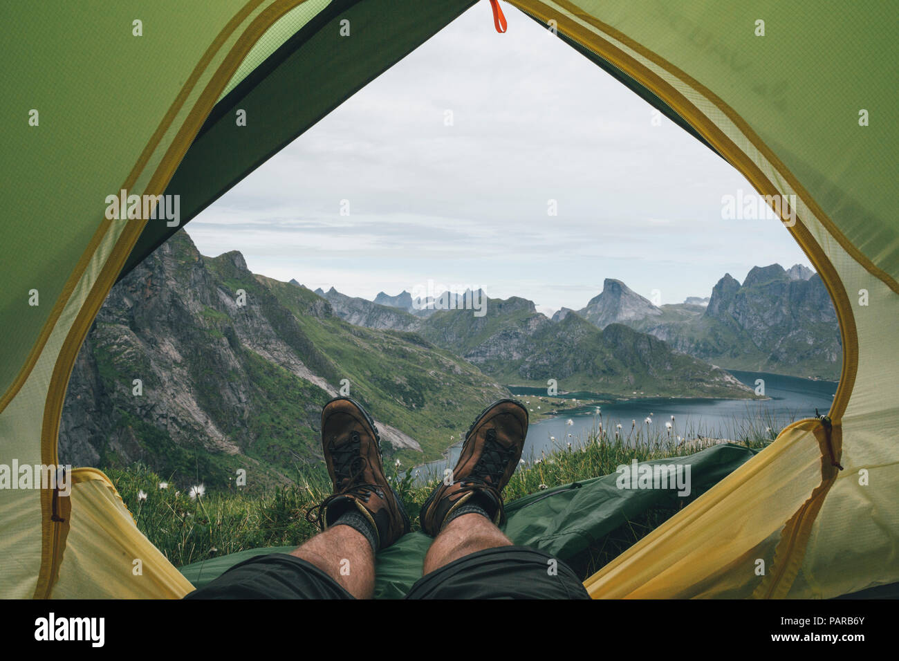 Norvegia Lofoten, Moskenesoy, piedi di uomo, giacente in una tenda sopra Kjerkefjord Foto Stock
