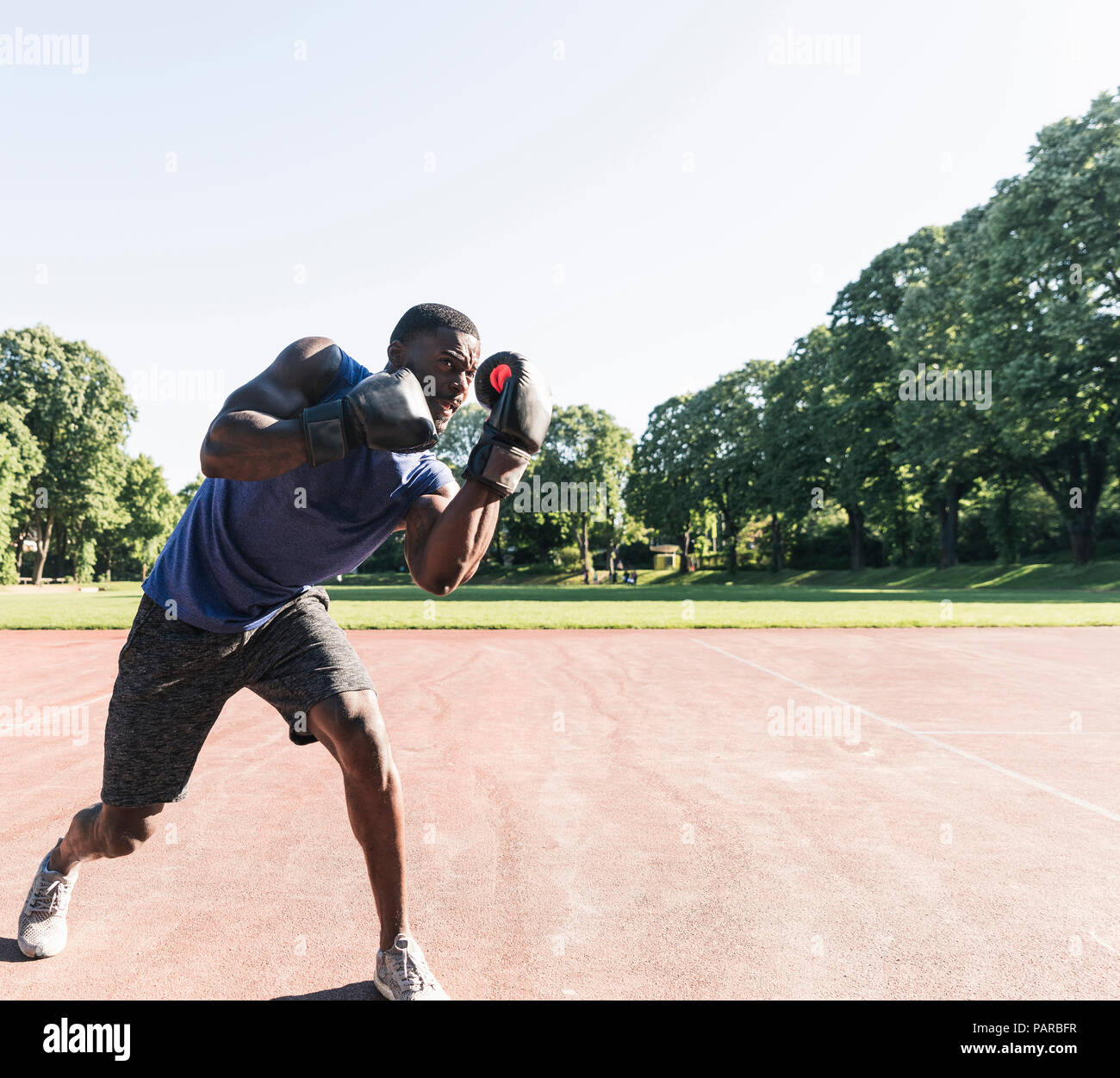 Giovane uomo afro-americana boxing training sul campo sportivo, all'aperto Foto Stock