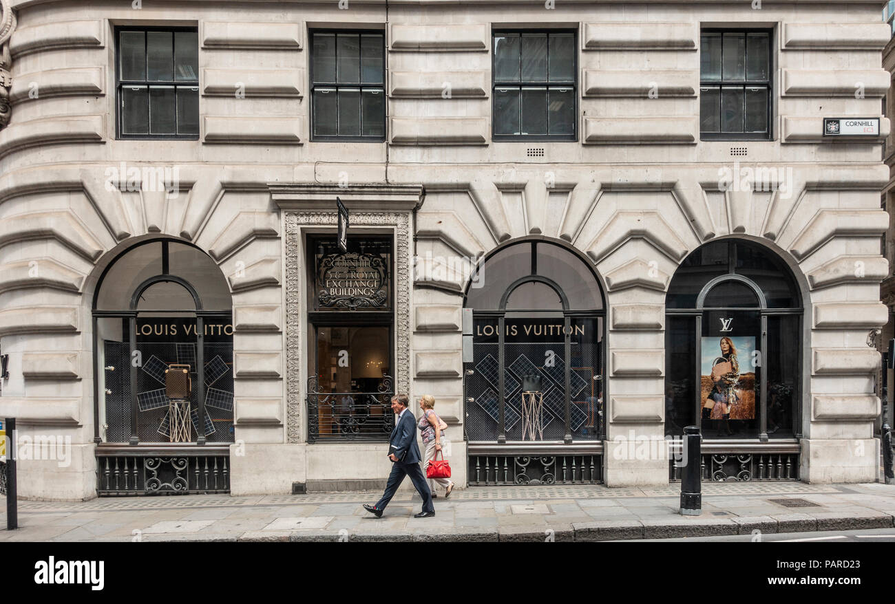 I pedoni a camminare lungo la Louis Vuitton designer shop in Royal Exhange edifici, Cornhill, Londra, Inghilterra. La finestra di visualizzazione, designer borse. Foto Stock