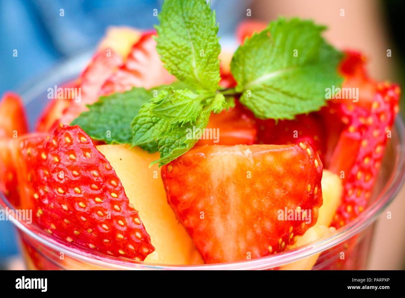Freschi e fragranti fette di bacche e frutti sono impilati in un contenitore. Melone giallo e rosso fragola. Il tutto è decorato con una fragrante crusca Foto Stock