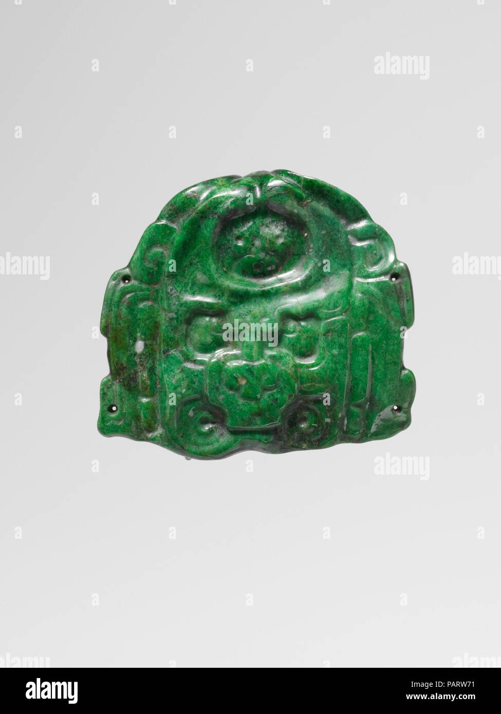Faccia una divinità di telecomando. Cultura: Maya. Dimensioni: H. 2 1/4 in. (5.7 cm). Data: 7th-8secolo. Questo apple-verde giada ornamento rappresenta la faccia aviaria di Ux Yop Hu'n ("tre foglie carta" o "Three-Leaf-carta") un complesso essendo soprannaturale che incarnò la fascia di carta indossati dagli antichi Maya i righelli. Questa figura è anche frequentemente indicata in letteratura come "l'foliated Jester Dio." Il suo fronte è infixed con un segno geroglifico che traduce come ajaw o righello (schematicamente una faccia composta di due punti per gli occhi e una per una bocca). Ux Yop Hu'n è mostrato cross-eyed, il suo allievo squadrato Foto Stock