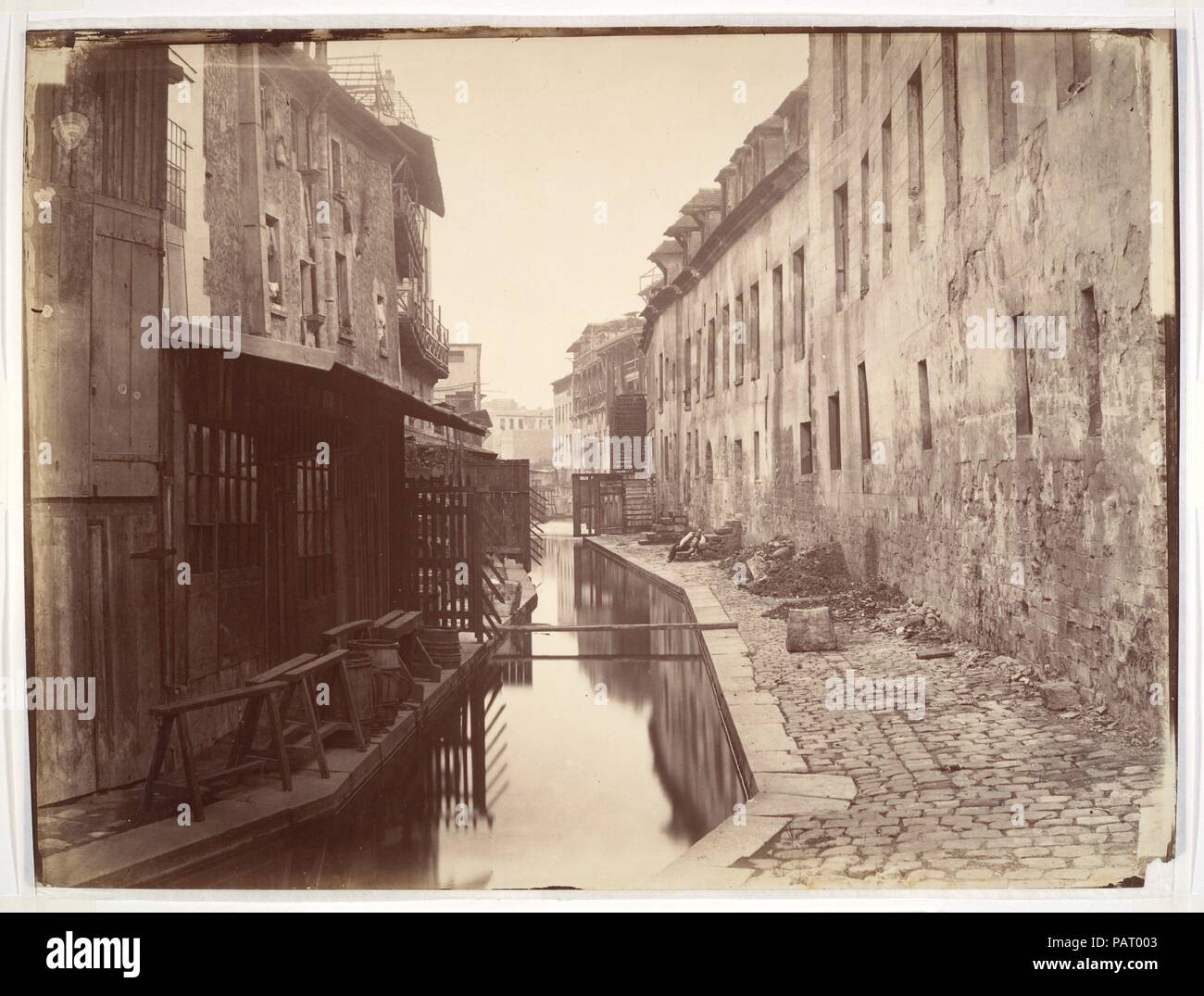 La Bièvre. Artista: Charles Marville (francese, Parigi Parigi 1813-1879). Dimensioni: 27,8 x 37,6 cm. (10 15/16 x 14 13/16 in.). Data: ca. 1865. Come ufficiale 'fotografo della città di Parigi,' Charles Marville era incaricato di documentare l'enorme trasformazione della città ha portato circa da Napoleone III e il suo urbanista, del Barone Haussmann. Nei primi anni 1850 l'imperatore ha proposto la creazione di una rete di grand boulevards che avrebbe aratro attraverso le strette strade tortuose e affollate baraccopoli di Parigi. Marville metodicamente registrato le strade e gli edifici slated per demolizione, preservando un i Foto Stock