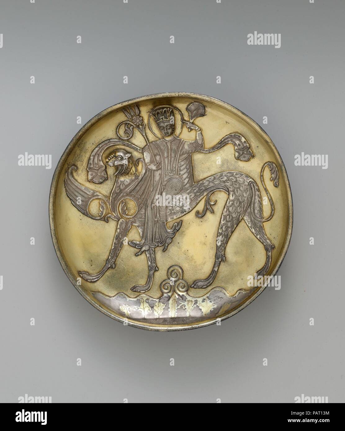 Piastra raffigurante una figura femminile a cavallo di un fantastico Bestia Alata. Dimensioni: H. 1 9/16 in. (4.0 cm) Diam. 8 1/8 in. (20,6 cm). Data: probabilmente VIII secolo. Come Sasaniane esempi, questa lastra raffigura una figura femminile a cavallo di un fantastico Bestia Alata con una testa felina, selvaggina di penna il corpo e le gambe canino. La sua figura è unnaturalistically twisted, una qualità visto su fine settima- e l'inizio dell'VIII secolo in Asia Centrale i dipinti murali da Panjikent. La parte inferiore della piastra contiene una rappresentazione simbolica della terra, acqua e cielo. Museo: Metropolitan Museum of Art di New York, Stati Uniti d'America. Foto Stock