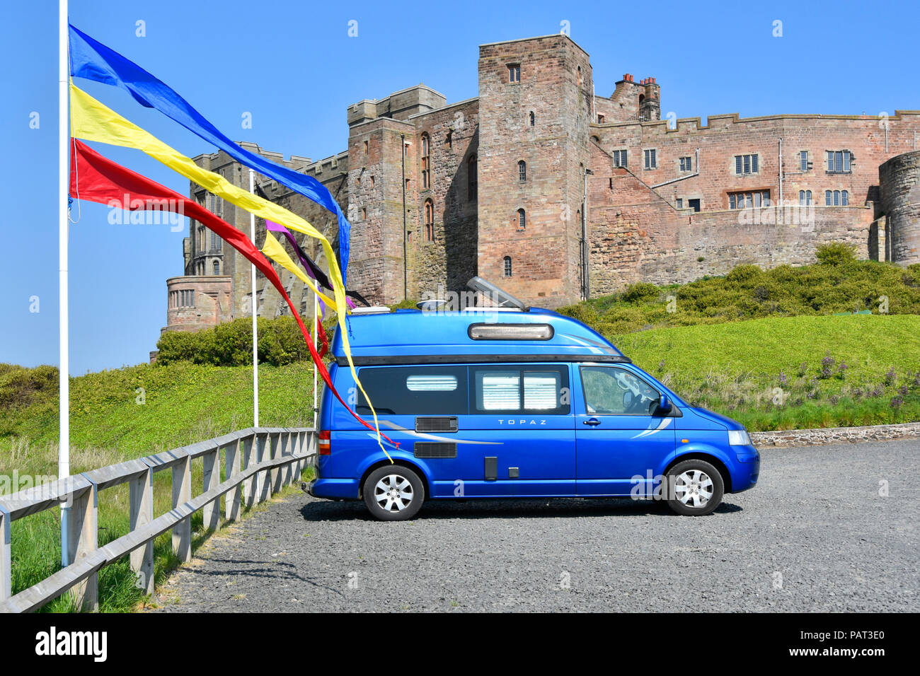 VW camper van visitatore turistico parco auto colorato pennant bandiere Bamburgh Northumberland Bamburgh storico castello Turismo & elencato la costruzione England Regno Unito Foto Stock