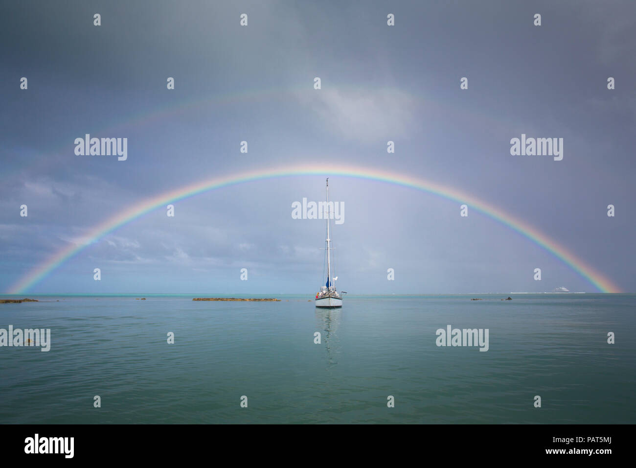 Isole di Cook, Aitutaki. Doppio arcobaleno con yacht. Foto Stock