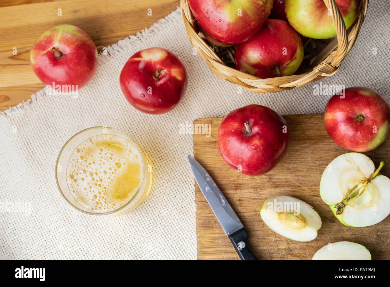 Vista superiore del mature mele succose e bicchiere di sidro drink sulla tavola in legno rustico. Bicchiere di fatto in casa e sidro coltivati localmente mele biologiche, girato da ab Foto Stock