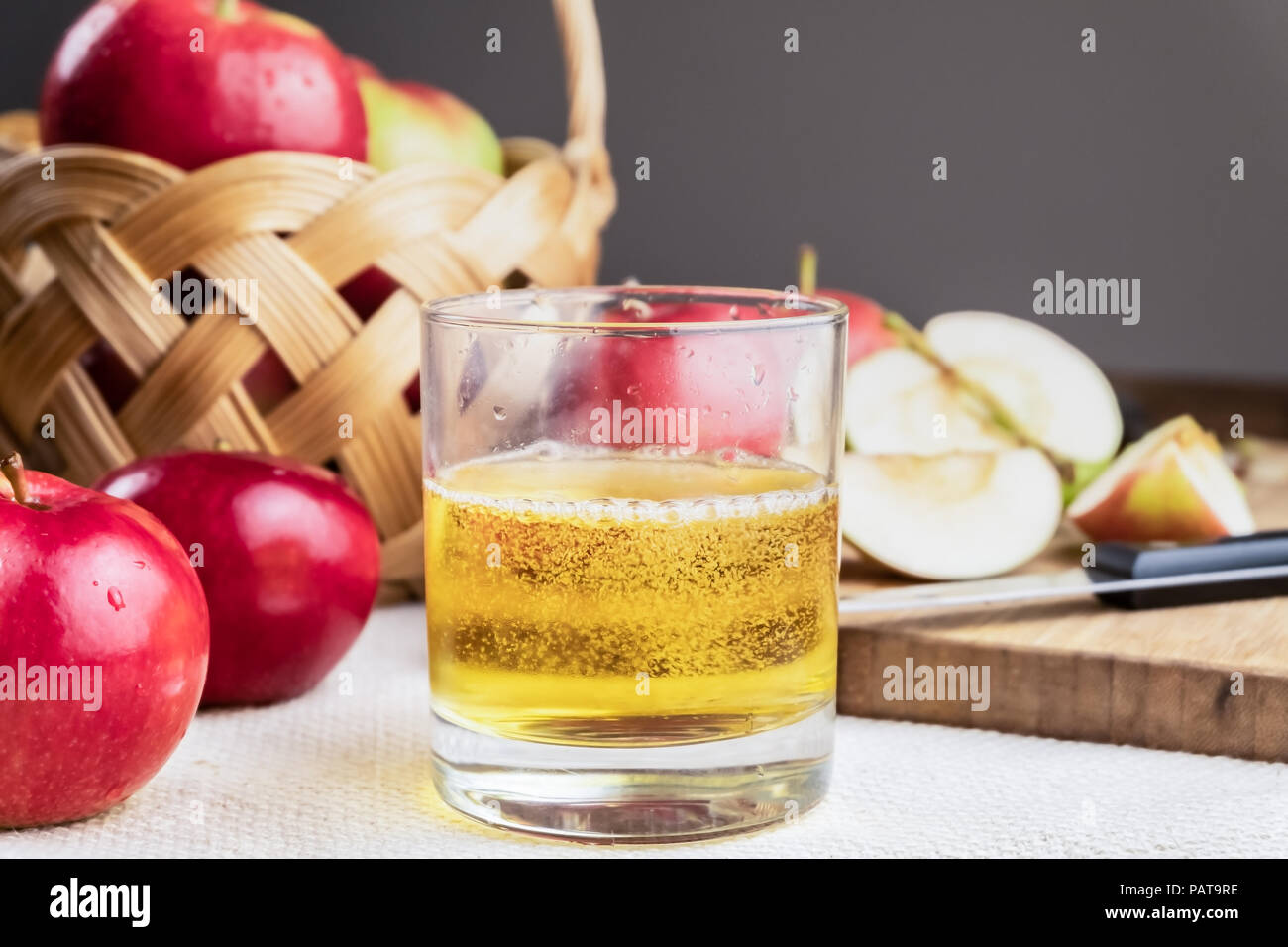 Close-up di immagine cidre bere e mature mele succose su tavola in legno rustico. Bicchiere di fatto in casa e sidro coltivati localmente mele biologiche Foto Stock