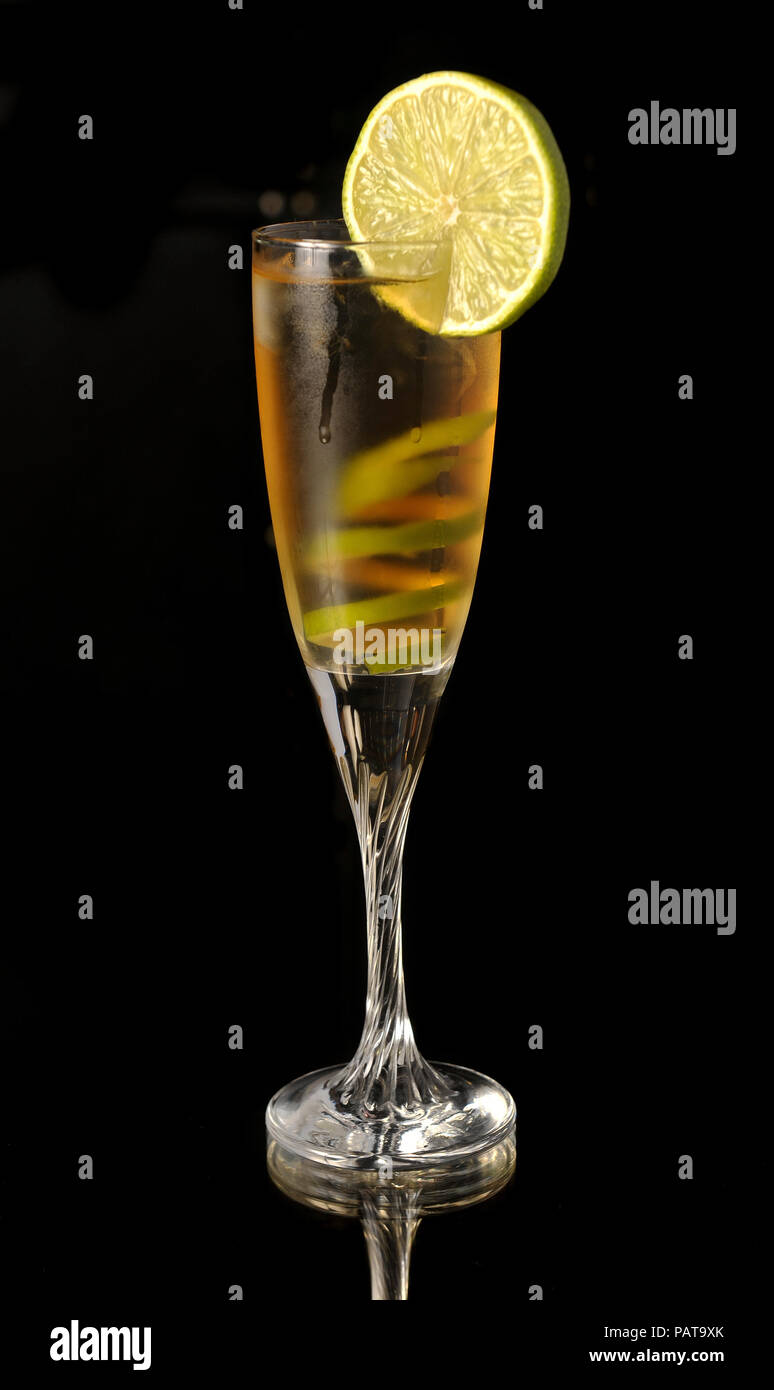 Cocktail giallo in vetro con calce twist su un nero Foto Stock