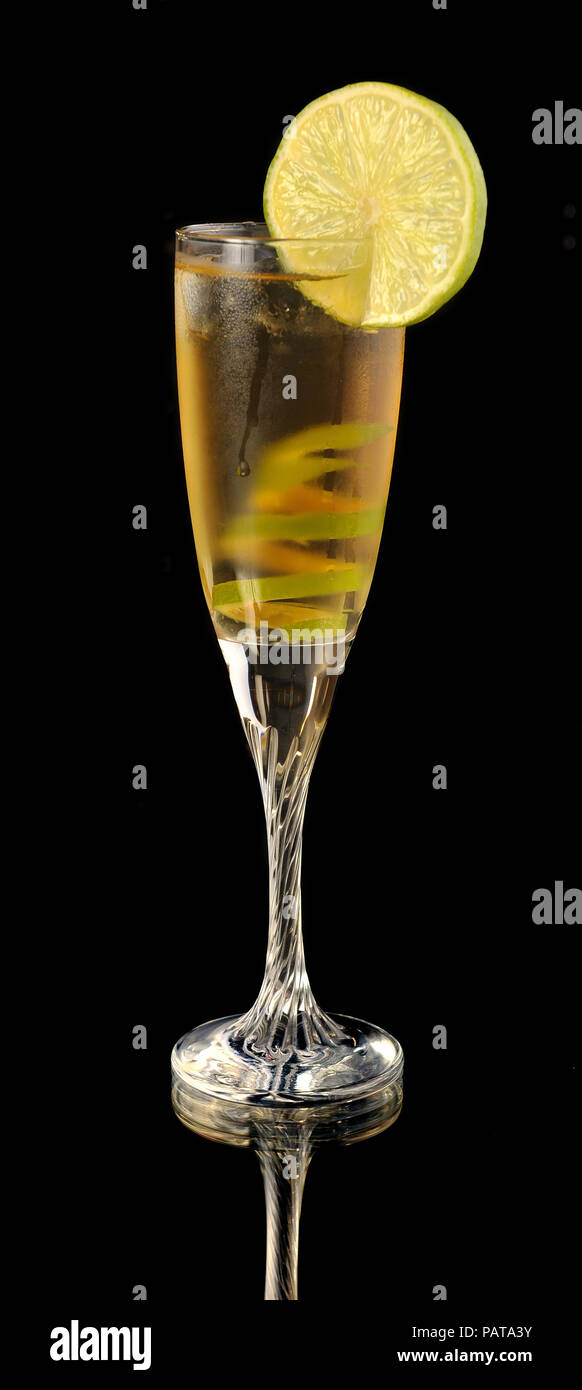 Cocktail giallo in vetro con calce twist su un nero Foto Stock