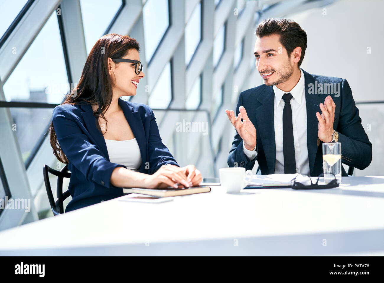 Imprenditrice e imprenditore parlando a scrivania in ufficio moderno Foto Stock