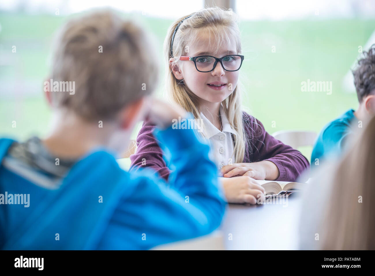 Ritratto di sorridere schoolgirl con i compagni di classe in classe Foto Stock