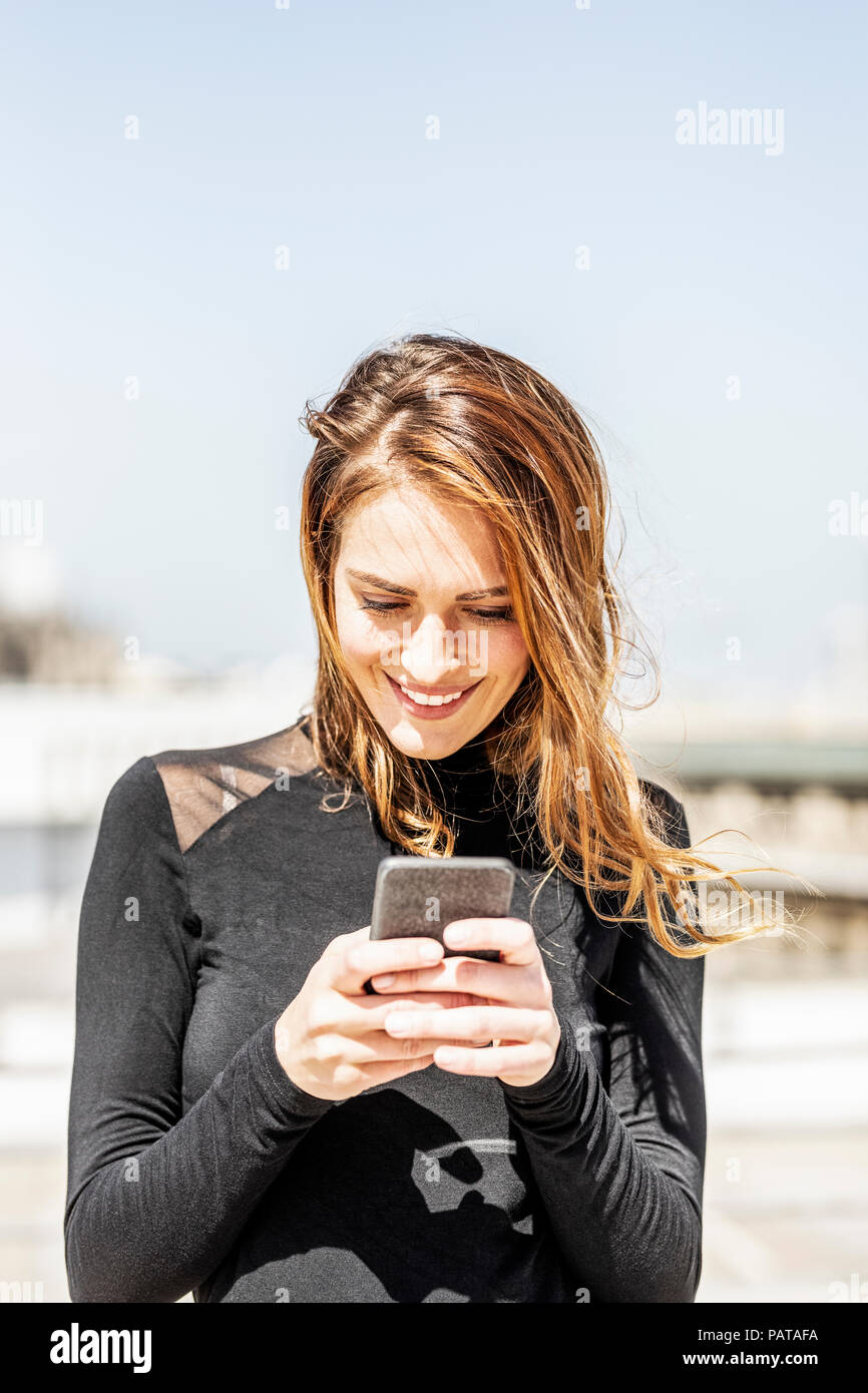 Ritratto di donna sorridente utilizza lo smartphone all'aperto Foto Stock