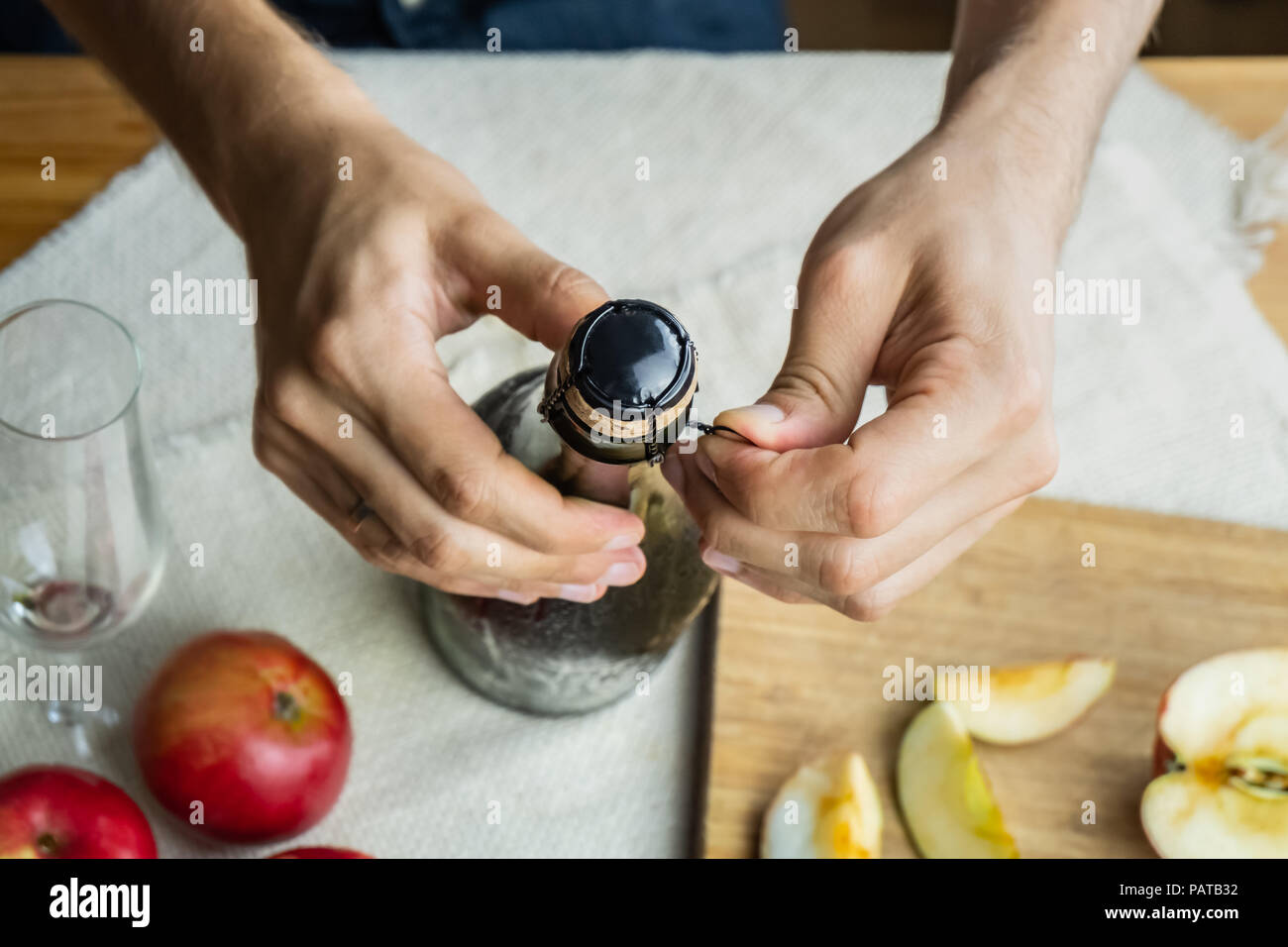 Vista superiore del maschio apertura mani bottiglia di sidro premium. Girato dal di sopra della stappatura bella di ghiaccio freddo bottiglia di vino di mela, coltivati localmente mela matura Foto Stock
