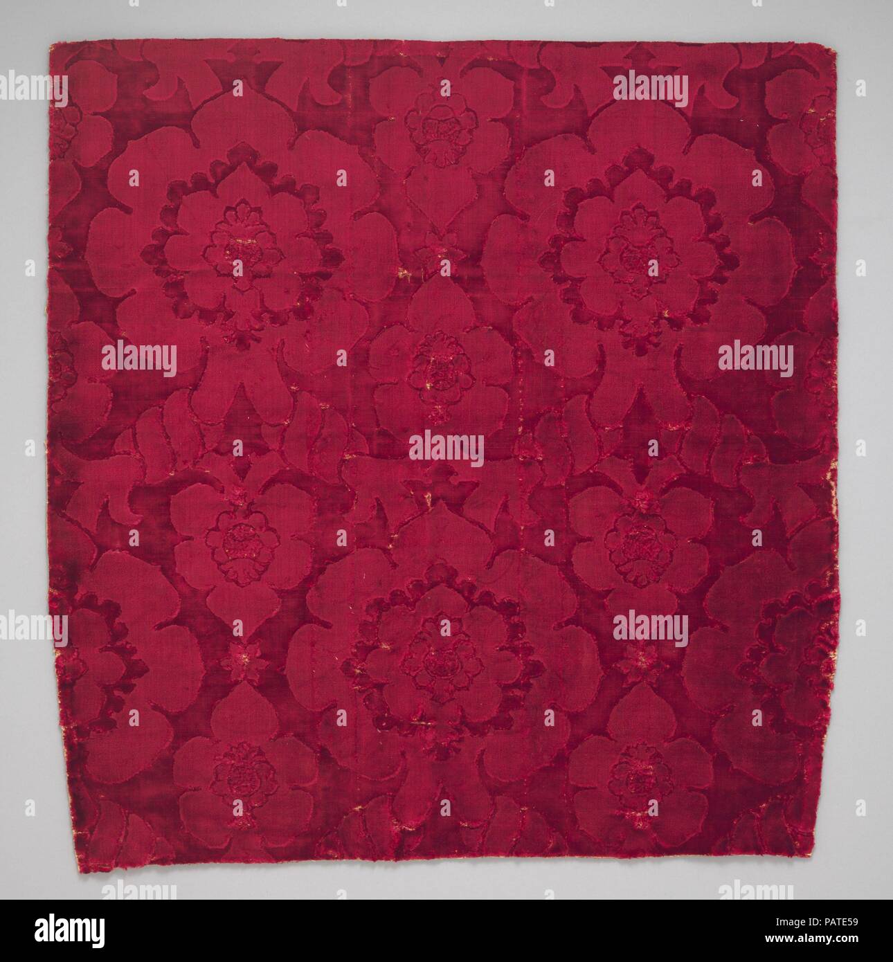 Pezzo. Cultura: Italiano, probabilmente a Venezia. Dimensioni: complessivo: 25 x 23 3/4 in. (63,5 x 60,3 cm). Data: XVI secolo. Il velluto con il modello delineato unicamente mediante il contrasto tra le due altezze della fitta velluto di seta pila è stata particolarmente popolare nel XVI secolo. Questo modello di palmettes lobata, talvolta incorporante corone, è stato trasformato in vesti o infissi indossato dal senatore della Repubblica Veneziana. Esso è stato anche usato per rendere i paramenti ecclesiastici. Il crimson ombra è associato con i senatori veneziani, ma il museo ha anche un esempio in tessuto profondo blu Seta. Museo: Me Foto Stock