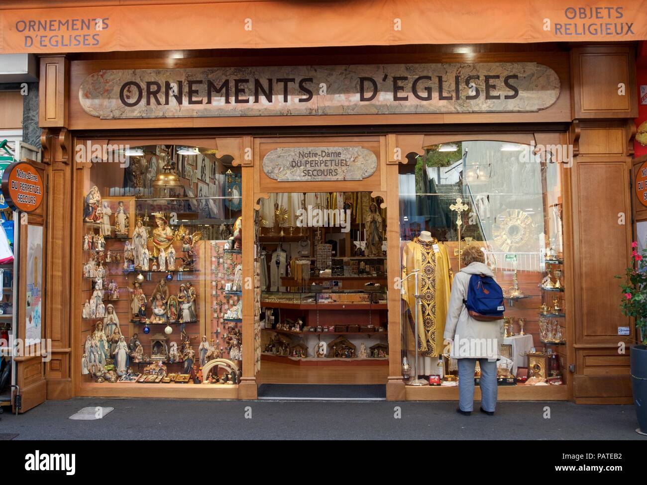 Una donna guarda gli articoli in vendita in un negozio di religiosi a Lourdes, Hautes Pirenei, Francia Foto Stock