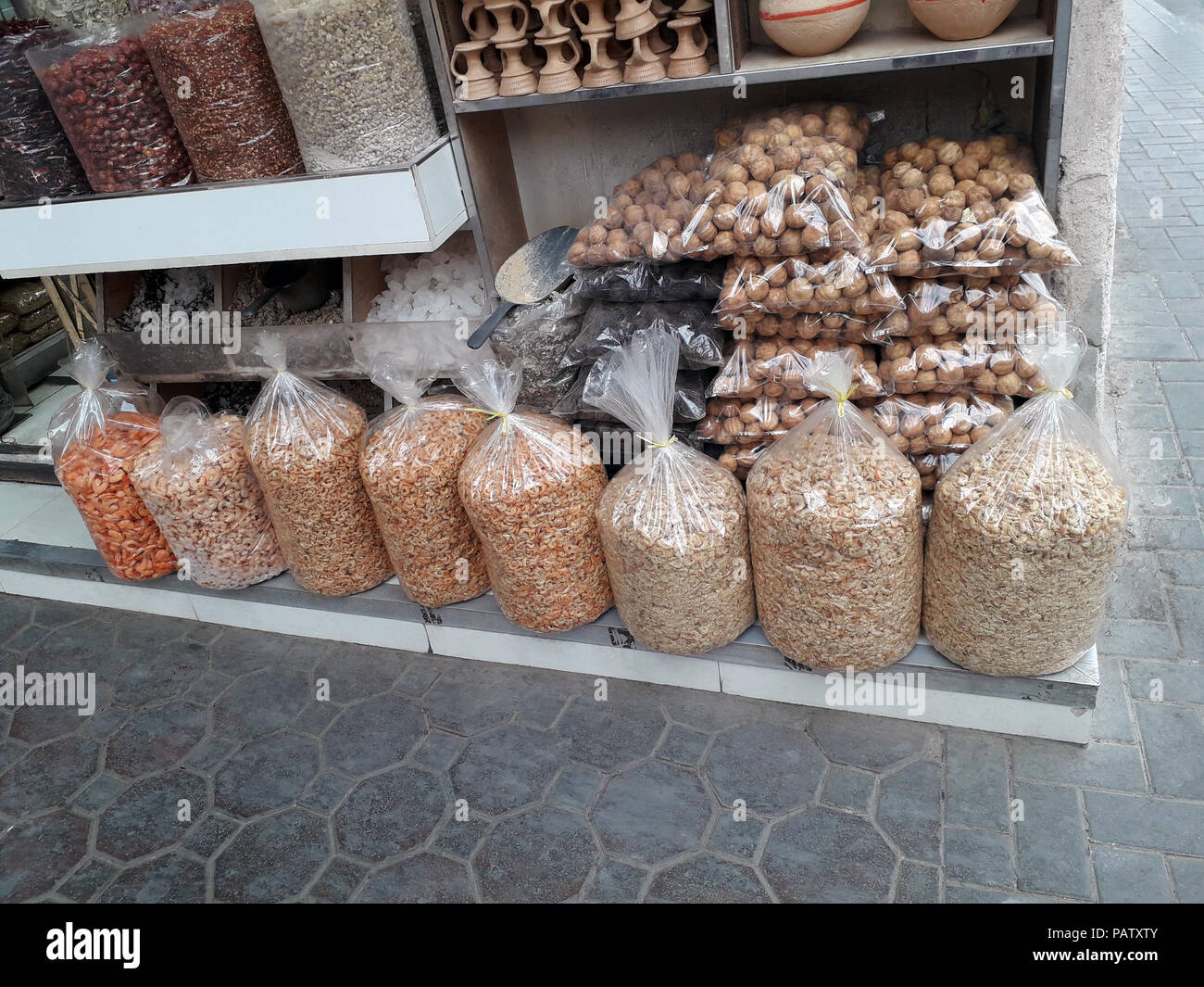 Gamberi secchi in buste trasparenti e con la buccia le noci in pacchetti, spezie in confezioni trasparenti in piedi sul contatore nel mercato in Deira, Dubai. Foto Stock