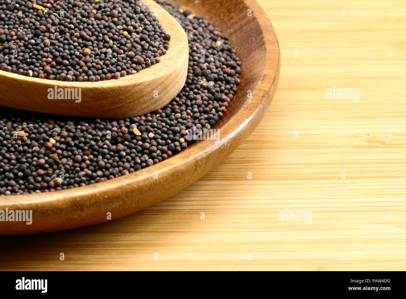 Nero Semi di senape su uno sfondo di legno Foto Stock