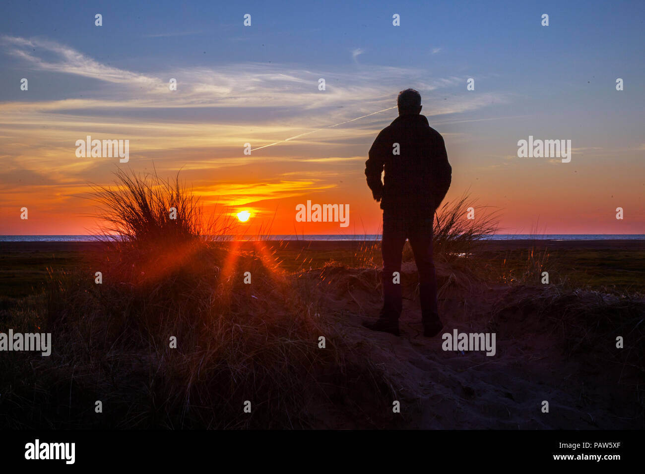 Southport, Merseyside Regno Unito 14 luglio, 2018. Silhouette uomo. Regno Unito Meteo. Colorato tramonto sul Mare d'Irlanda e Ainsdale dune di sabbia riserva naturale nazionale (NNR), che è un 508 ettari comprendente rare dune, spiaggia e gli habitat forestali. Ci sono 10 km di sentieri segnati da seguire, un tranquillo e selvaggio circondato da uno dei la maggior parte delle aree urbane in Inghilterra. Credito: MediaWorldImages/Alamy Live News Foto Stock