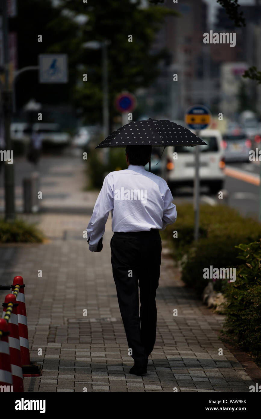 Nagoya, Giappone. Luglio 25, 2018 - Un uomo utilizza un ombrellone per evitare il sole in Nagoya, Giappone. Alte temperature è proseguito per tutto il paese su mercoledì. La Japan Meteorological Agency ha dichiarato la costante ondata di calore di un disastro naturale, con 65 decessi segnalati nel corso della settimana passata. L'agenzia ha previsto ha continuato a temperature elevate nelle prossime settimane. Credito: Ben Weller/AFLO/Alamy Live News Foto Stock