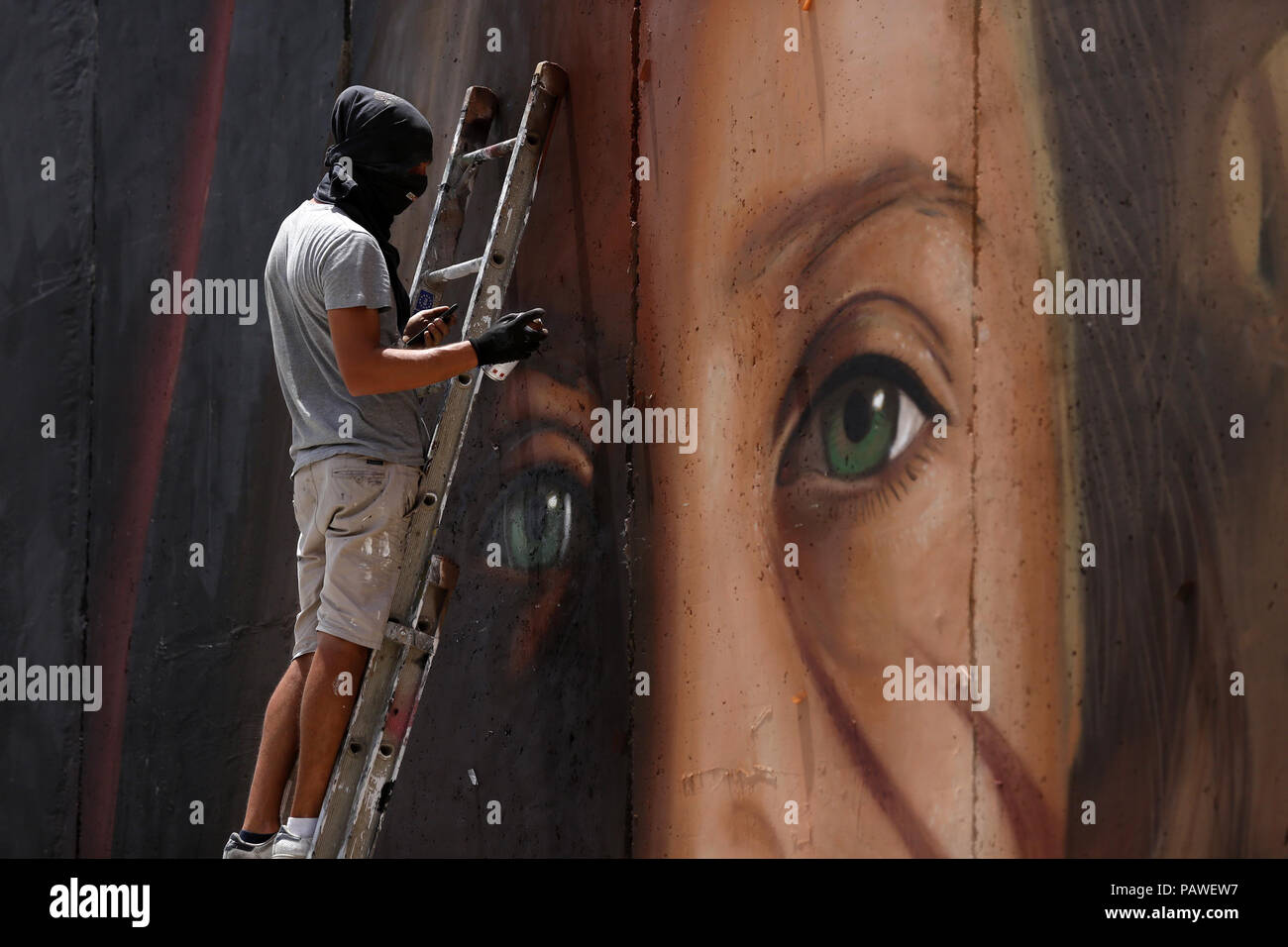 Betlemme, West Bank. Xxv Luglio, 2018. Artista italiano Jorit Agoch dipinge un murale raffigurante ragazzo palestinese Ahed Tamimi su Israele la controversa barriera di separazione in Cisgiordania città di Betlemme. Tamimi, è stato caricato in precedenza quest'anno dopo un video virale ha mostrato il suo colpendo due soldati nei territori occupati della Cisgiordania. Credito: Wisam Hashlamoun APA/images/ZUMA filo/Alamy Live News Foto Stock