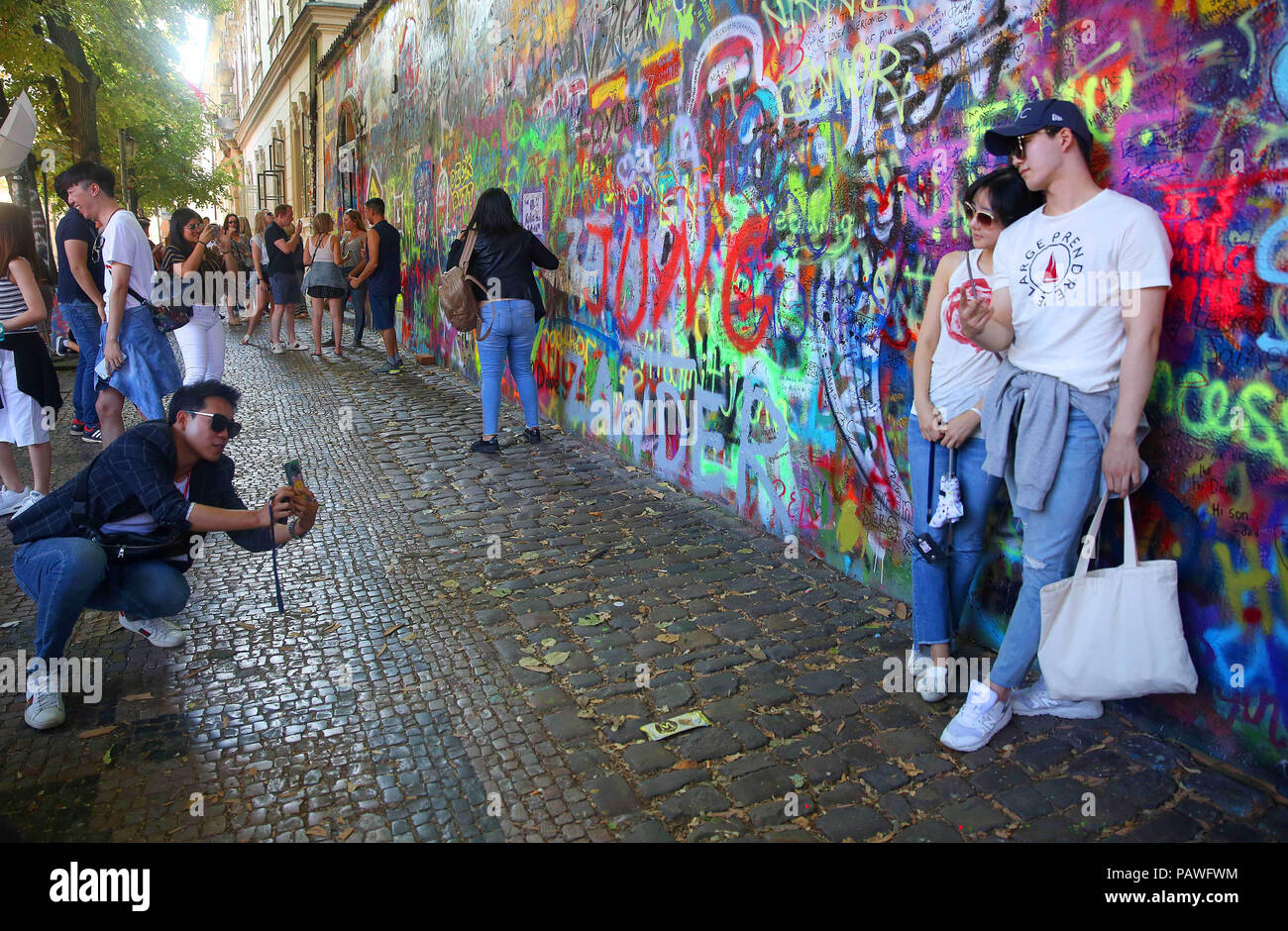 Praga, Repubblica Ceca. 14 Luglio, 2018. I turisti pongono di fronte alla parete di Lennon o John Lennon parete è una parete a Praga, Repubblica Ceca. Una volta che una normale parete, sin dagli anni ottanta è stato riempito con John Lennon-ispirato graffiti e pezzi di testi dal Beatles" canzoni. Credito: Leigh Taylor/ZUMA filo/Alamy Live News Foto Stock