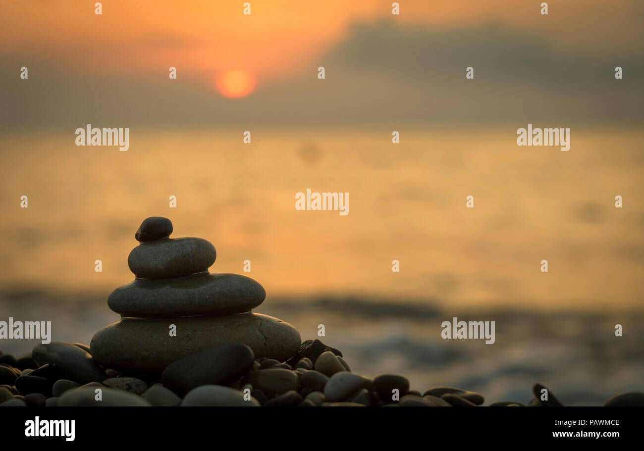 Piramide piegata Zen pietre ghiaia sul mare spiaggia al tramonto Foto Stock