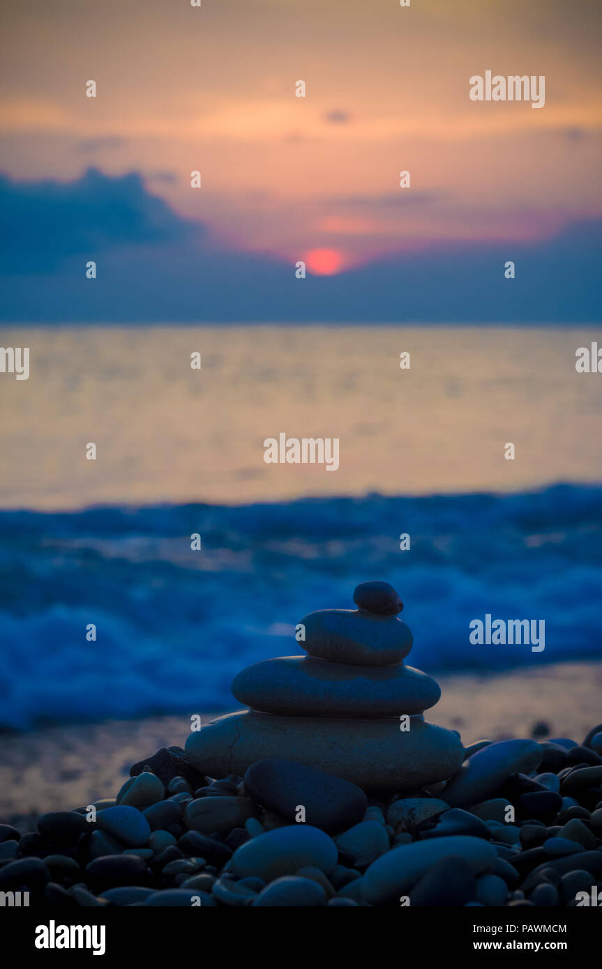 Piramide piegata Zen pietre ghiaia sul mare spiaggia al tramonto Foto Stock