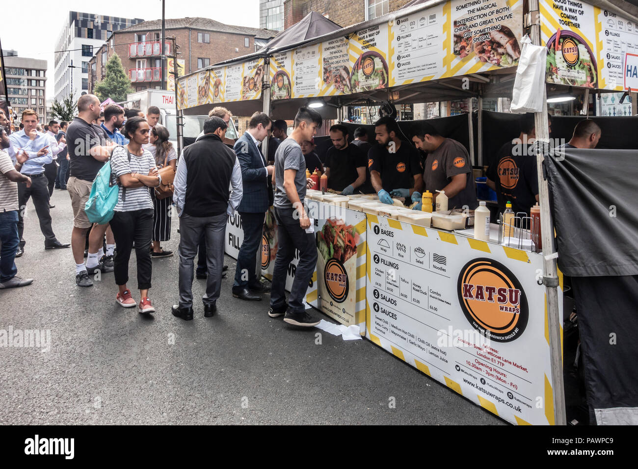 I lavoratori e i locali accodamento in un Katsu avvolge Asian street food in stallo Petticoat Lane market in Spitalfields nell'East End di Londra, Inghilterra, Regno Unito. Foto Stock