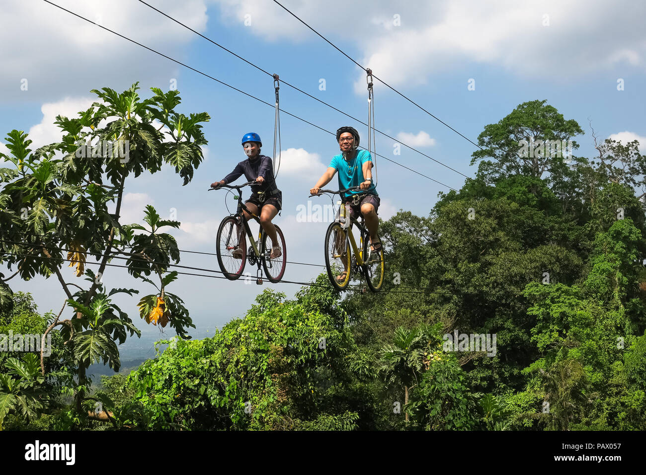 Bataan - Filippine - Aprile 8, 2016: una coppia corrono in bici attraverso il cielo, alta su un filo sospeso sopra una giungla canyon presso Sinagtala Farm Resort. Foto Stock