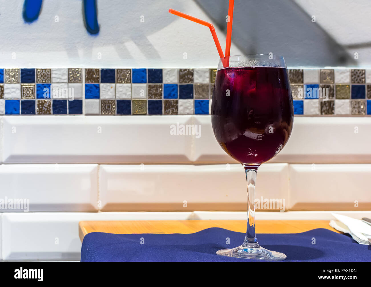 Bicchiere pieno di profondo rosso Sangria vino con due cannucce rosso sul bianco Sfondo piastrelle. La sangria è una bevanda alcolica di origine spagnola. Foto Stock