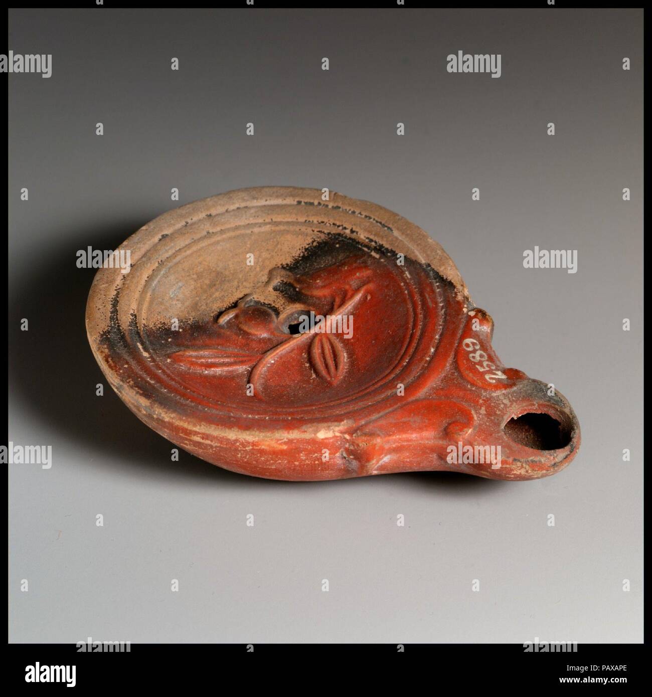 Olio di terracotta con lampada. Cultura: romana, cipriota. Dimensioni: complessivo: 7/8 x 3 1/2 in. (2,2 x 8,9 cm). Data: 1° secolo a.c.-1st secolo D.C.. Loeschcke Tipo 4. Stampo-fatta. Discus: un uccello, rivolto verso sinistra, arroccata sulle estremità di una filiale di grandi dimensioni con due foglie e un acino; un unico foro di riempimento vicino al centro tra Bird e berry, e una fascia di linee e di scanalature verso il bordo. Coclee di ugello di accompagnamento. Incisa anello di base e base piana. Intatto. Museo: Metropolitan Museum of Art di New York, Stati Uniti d'America. Foto Stock