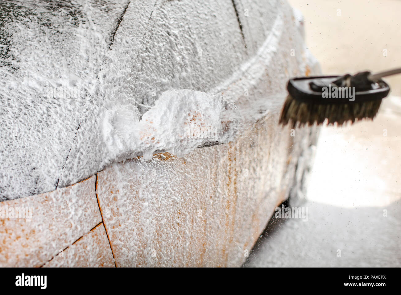 Schiuma e shampoo spruzzo da spazzola per lo specchietto laterale di un auto in self service carwash. Foto Stock