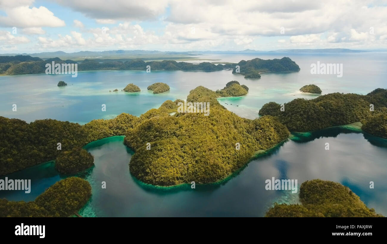 Vista aerea: spiaggia, isola tropicale, Baia Mare e laguna, Siargao. Paesaggio tropicale hill, nuvole e montagne rocce con la foresta pluviale. Acque azzurre della laguna. Paesaggio Shore Bay. Concetto di viaggio. Foto Stock