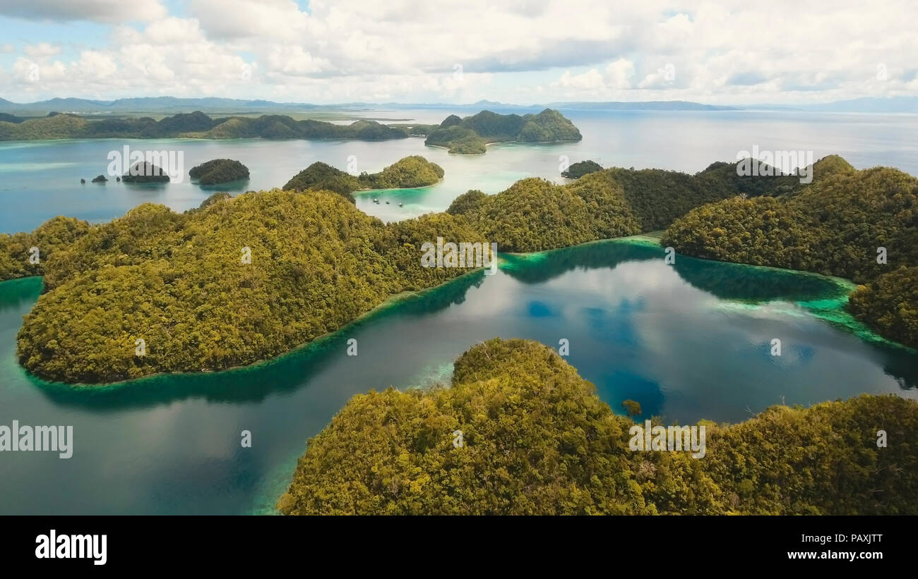 Vista aerea: spiaggia, isola tropicale, Baia Mare e laguna, Siargao. Paesaggio tropicale hill, nuvole e montagne rocce con la foresta pluviale. Acque azzurre della laguna. Paesaggio Shore Bay. Concetto di viaggio. Foto Stock