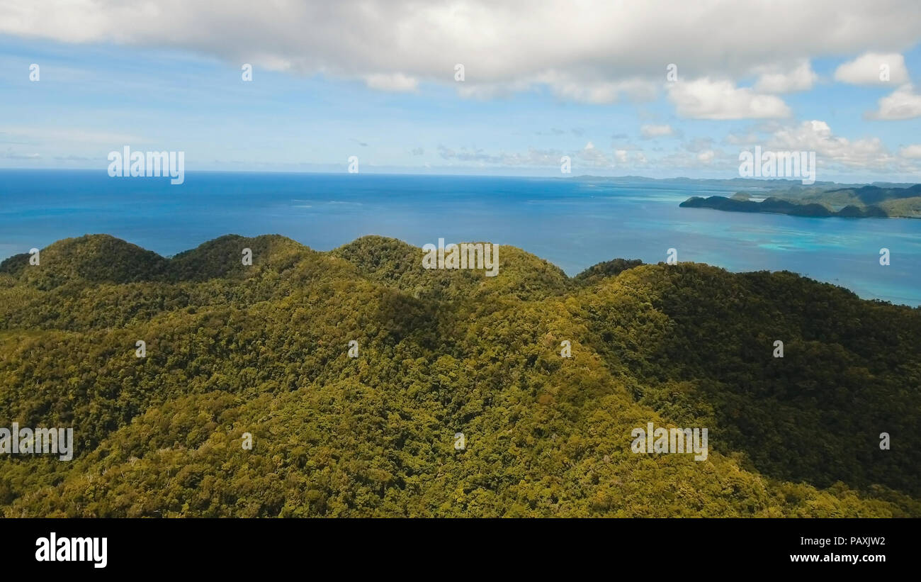 Vista aerea: spiaggia, isola tropicale, Baia Mare e laguna, Siargao. Paesaggio tropicale hill, nuvole e montagne rocce con la foresta pluviale. Acque azzurre della laguna. Paesaggio Shore Bay. Concetto di viaggio. Foto Stock