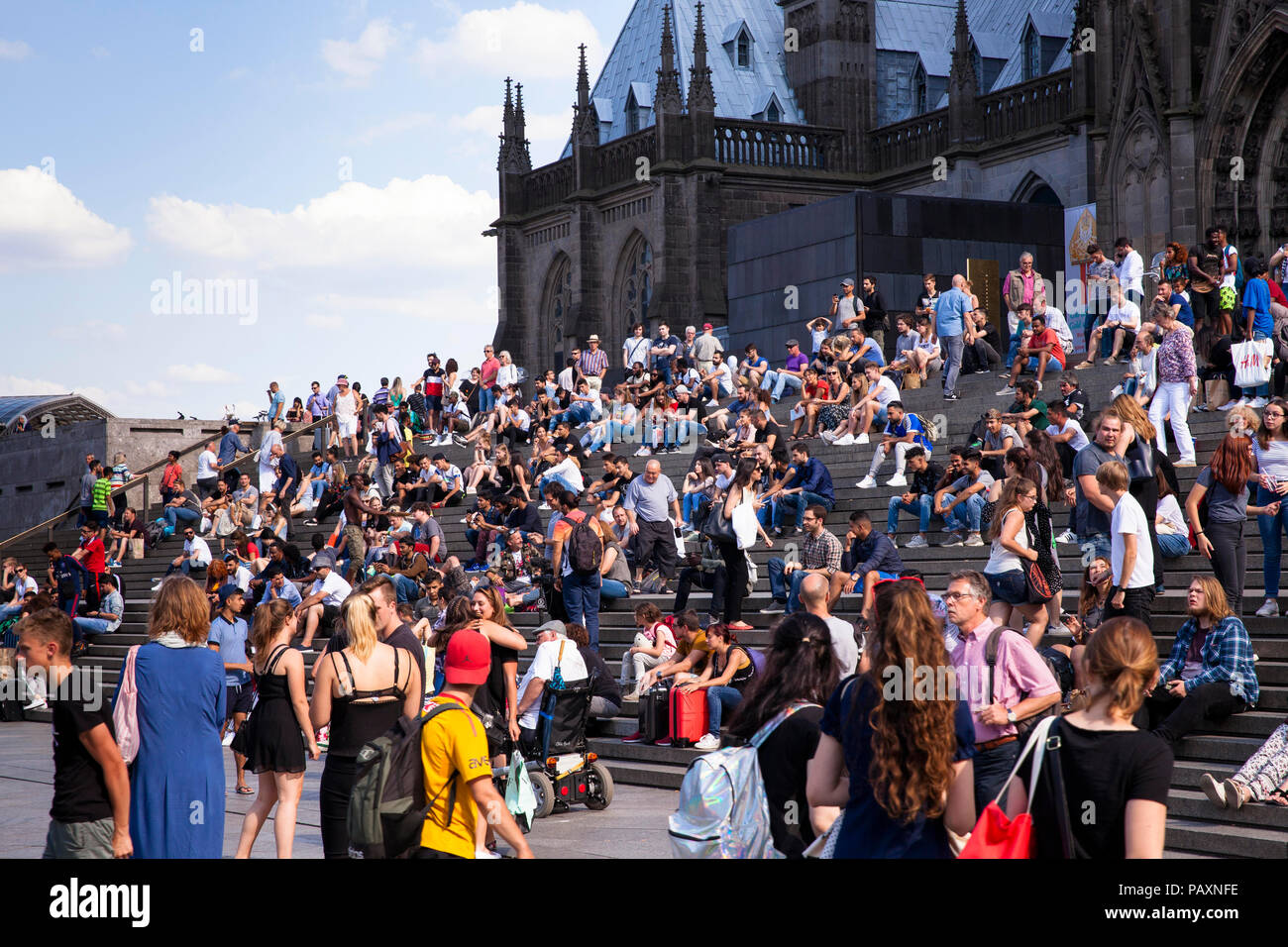 La gente seduta sulle scale formano la piazza del Duomo per la stazione principale di Colonia, Germania. Menschen sitzen auf der Treppe von der Domplatte zum ha Foto Stock