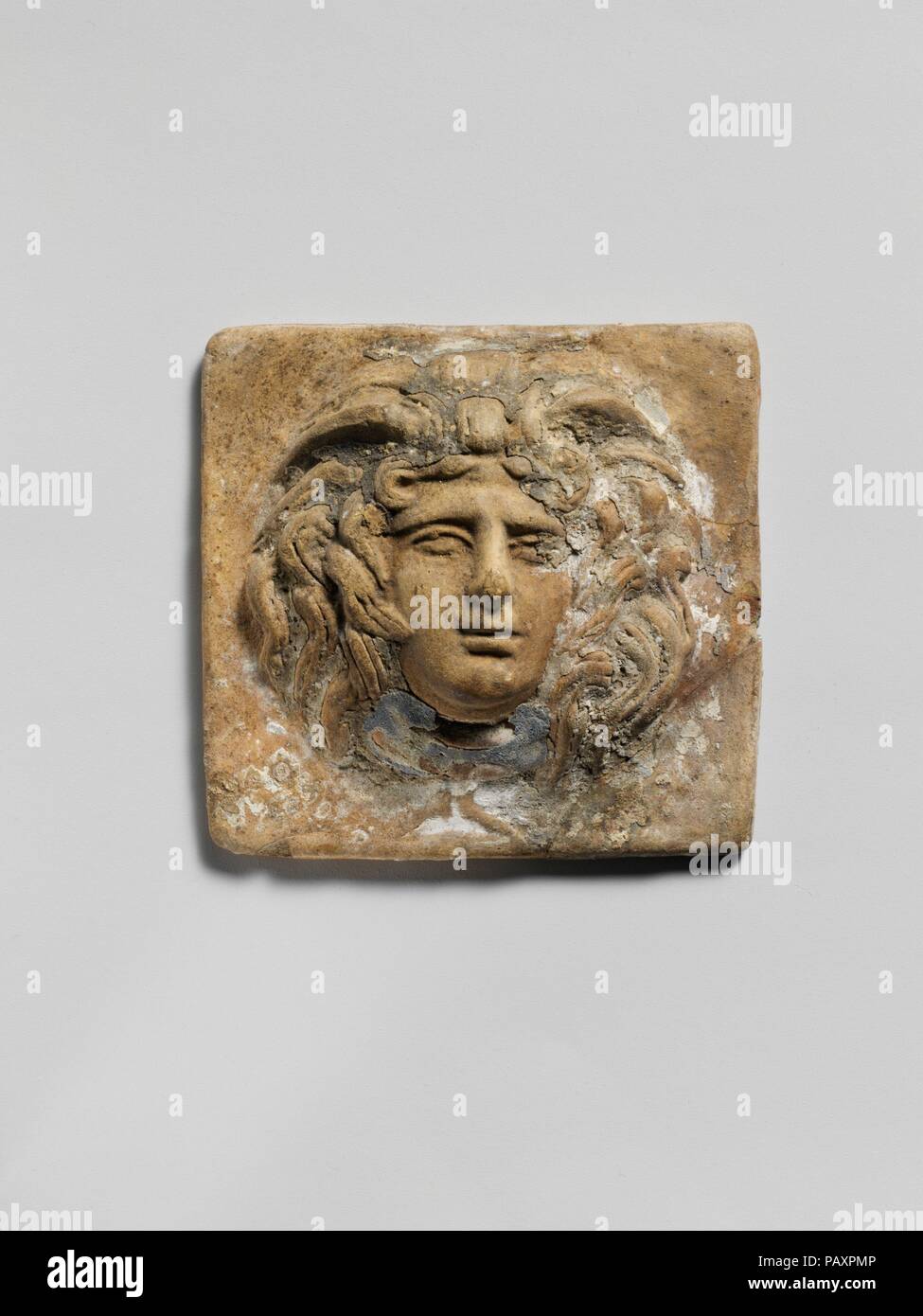In terracotta di placca in rilievo con la testa di Medusa. Cultura: greco. Dimensioni: H. 2 7/16 in. (6.2 cm.) L. 2 1/2 in. (6.4Cm.). Data: 2° secolo A.C. Leggermente scheggiato. Un buon affare di pigmento blu rimane sulla gola e un po' sopra la testa. Museo: Metropolitan Museum of Art di New York, Stati Uniti d'America. Foto Stock